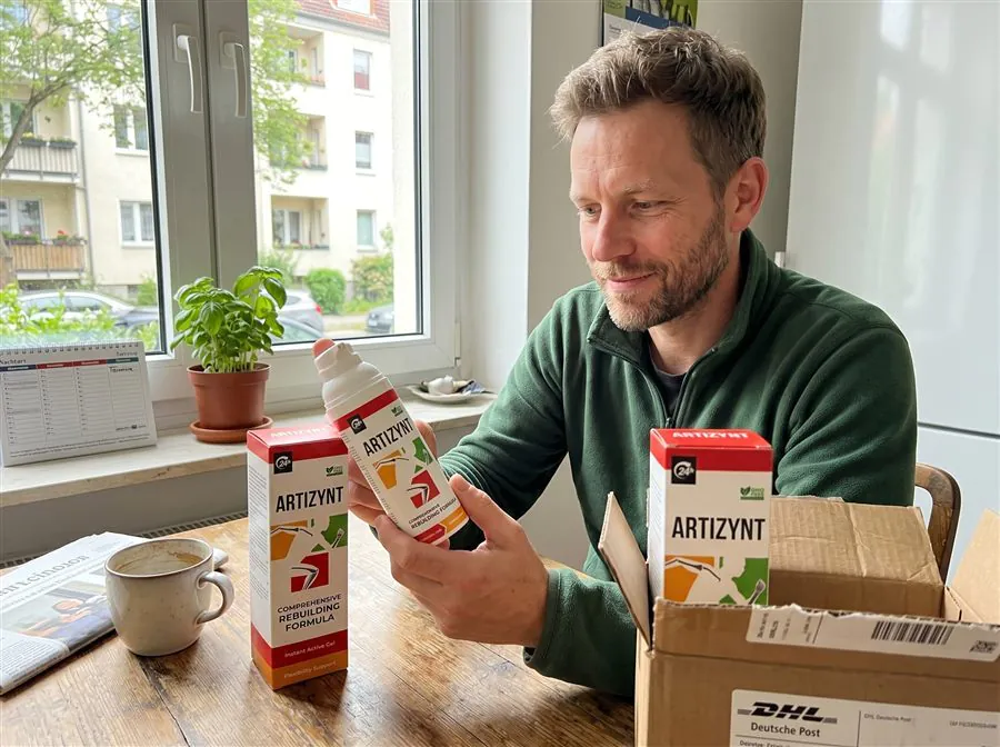 Kunde mit ArtiZynt Gel und DHL-Paket der Deutschen Post am Küchentisch